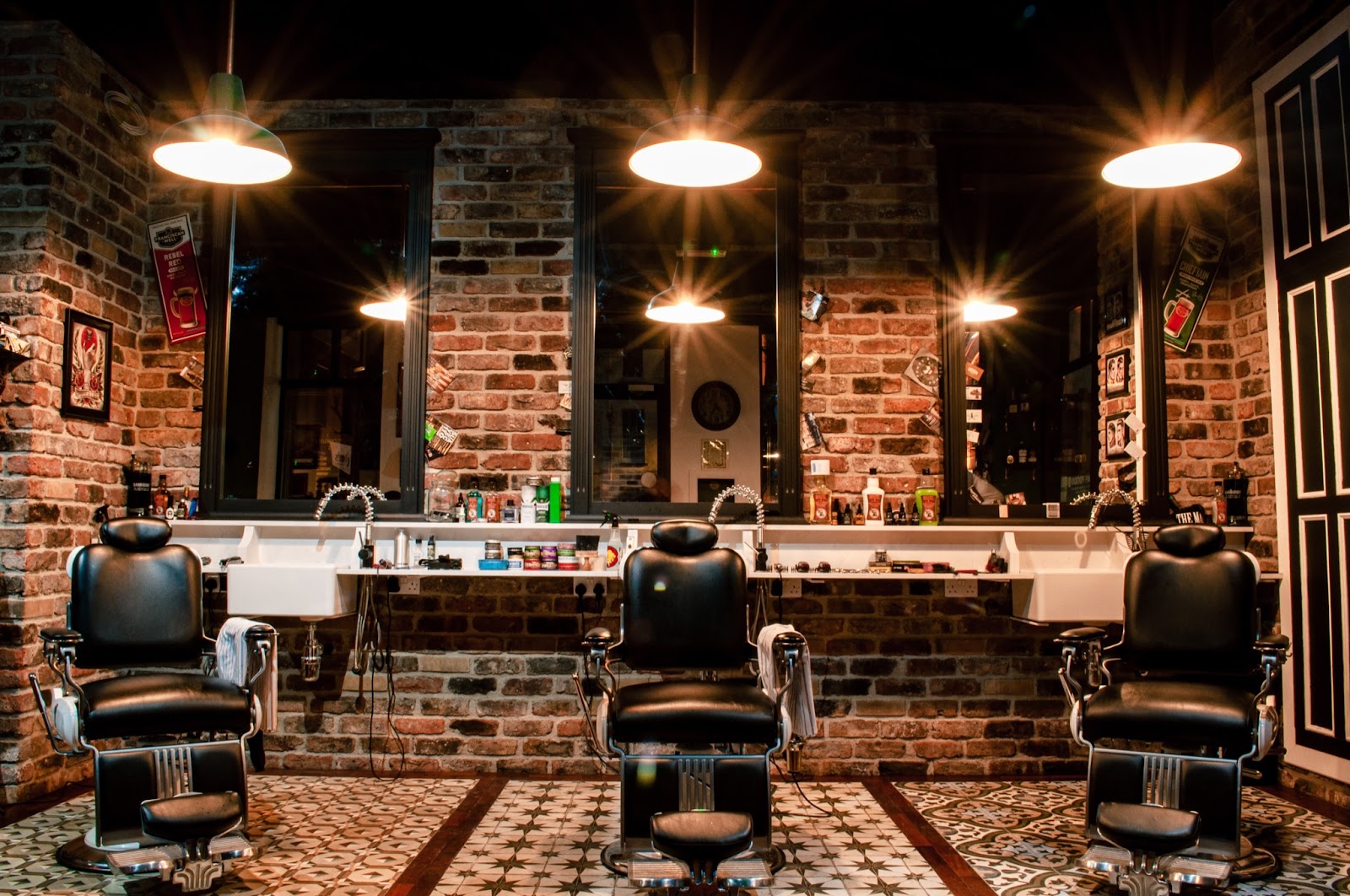 three black barber chairs in a barbershop with brickwalls